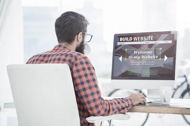 Man working on a website builder interface on a desktop computer.