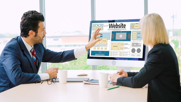 Business professionals discussing website layout on a desktop screen.