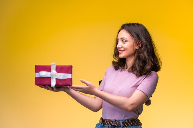 Young girl holding a gift box, smiling happily on her anniversary celebration.